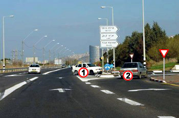 תמונה לשאלת תיאוריה: הרכב הלבן (1) שבצומת והרכב הכסוף (2) מתכוונים להיכנס לאותה דרך. מי מהם חייב לתת זכות קדימה?